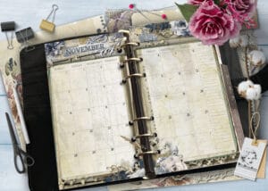 Open planner with November calendar pages, surrounded by decorative scrapbook supplies and pink flowers.