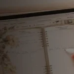 Vintage-style digital planner displayed on an iPad with handwritten notes, coffee, and stationery on a wooden desk