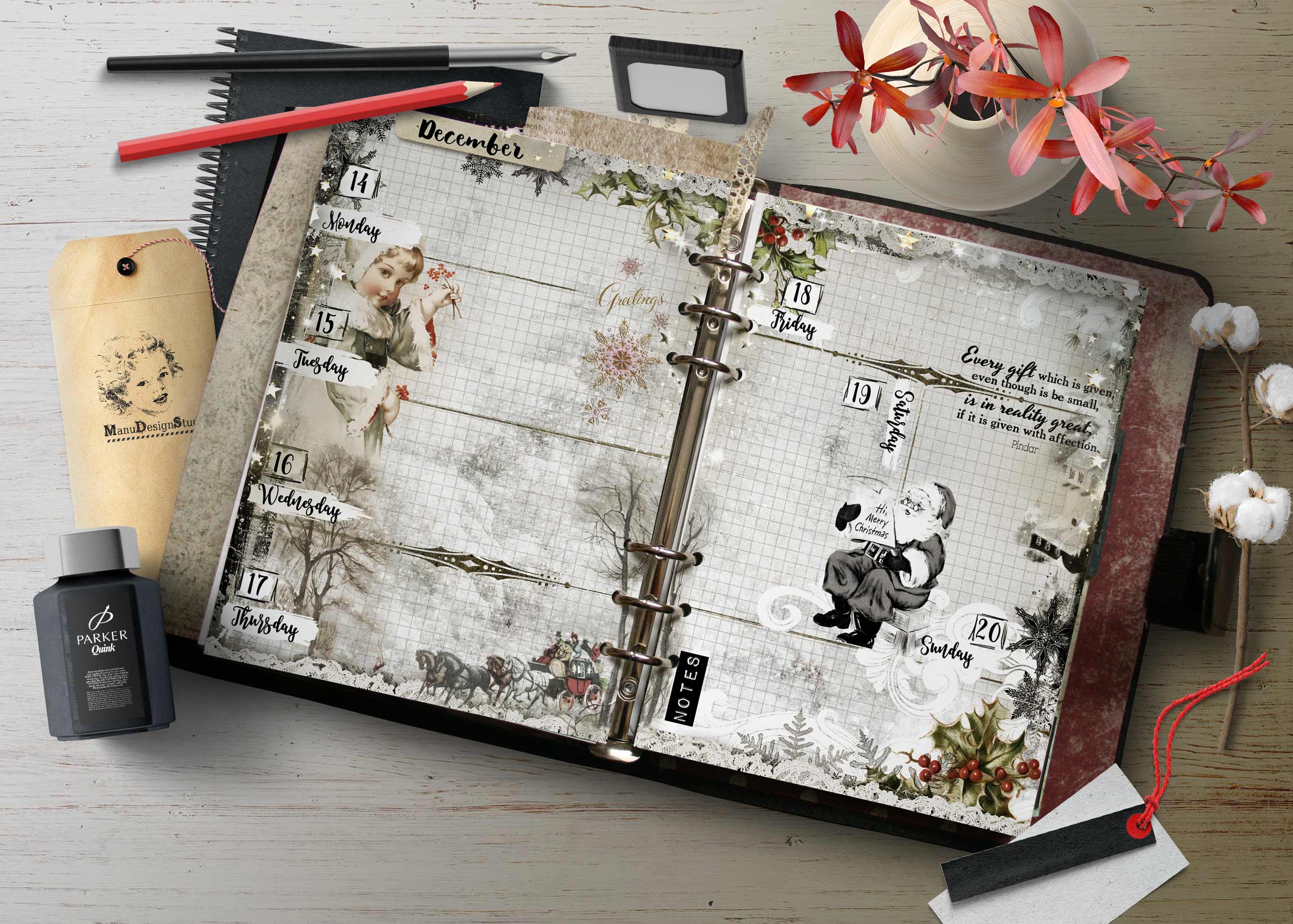 Open decorative planner spread on a light wooden desk, surrounded by pens, a tag, and pink flowers with winter imagery.