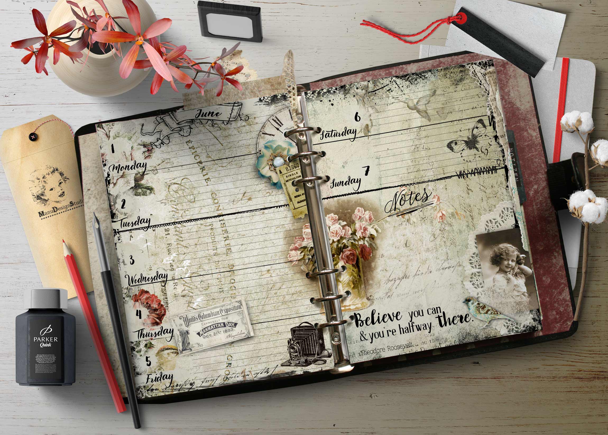Open vintage planner on a wooden desk with pink flowers and assorted stationery nearby.