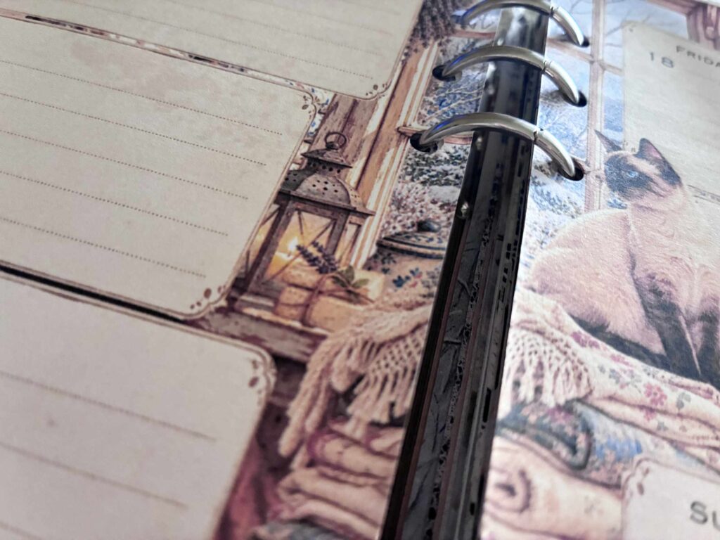 Open ring binder with cozy cat planner pages and lantern illustration